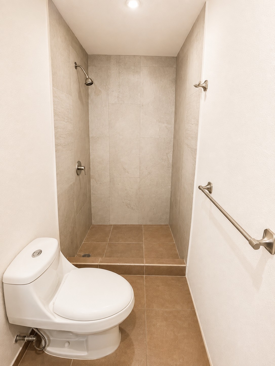 Baño con ducha revestida y acabados neutros